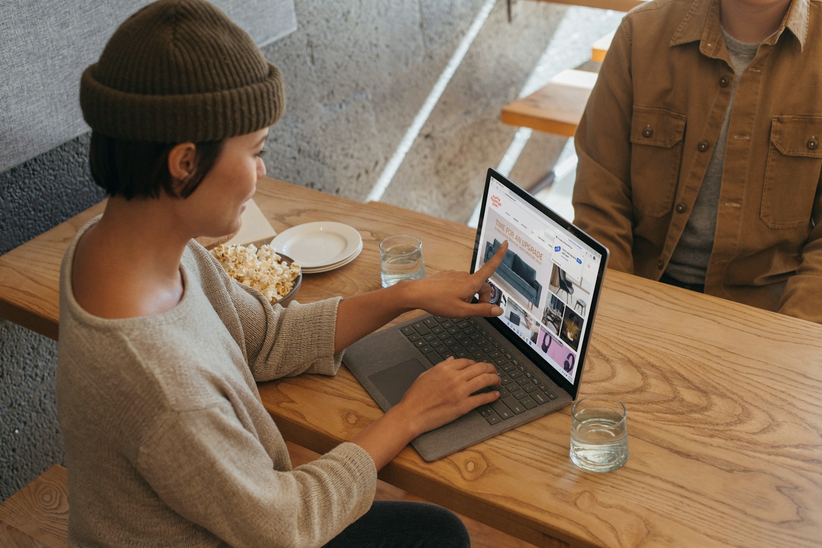 Two colleagues collaborating across a desk with a laptop